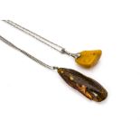 An early 20th Century white metal mounted amber boulder pendant, in toffee colour, together with a