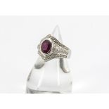 A contemporary 18ct white gold ruby and diamond dress ring, the oval mixed cut ruby in collet