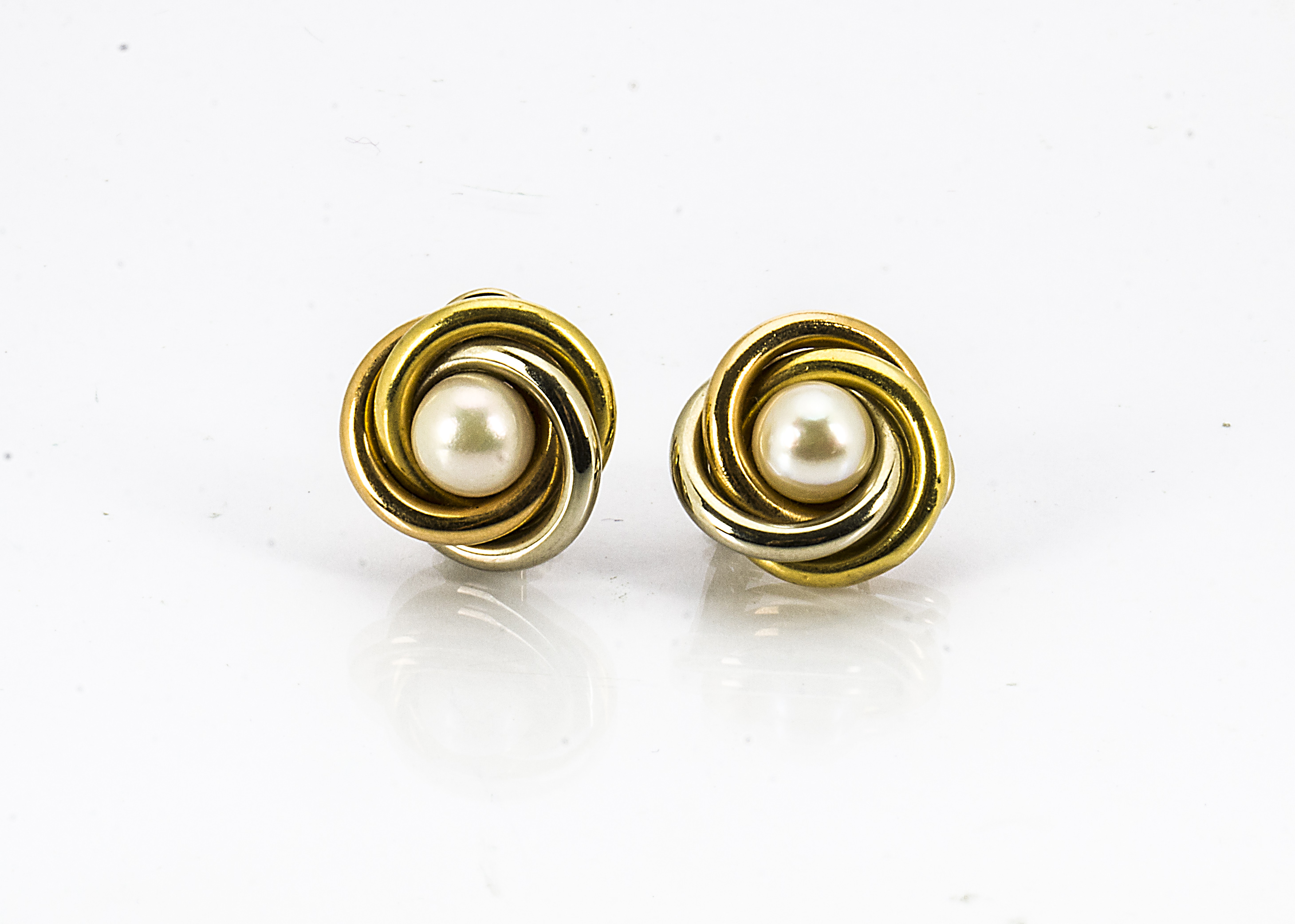 A pair of 18ct gold two colour ear studs, of knot design centred with cultured pearls, marked to