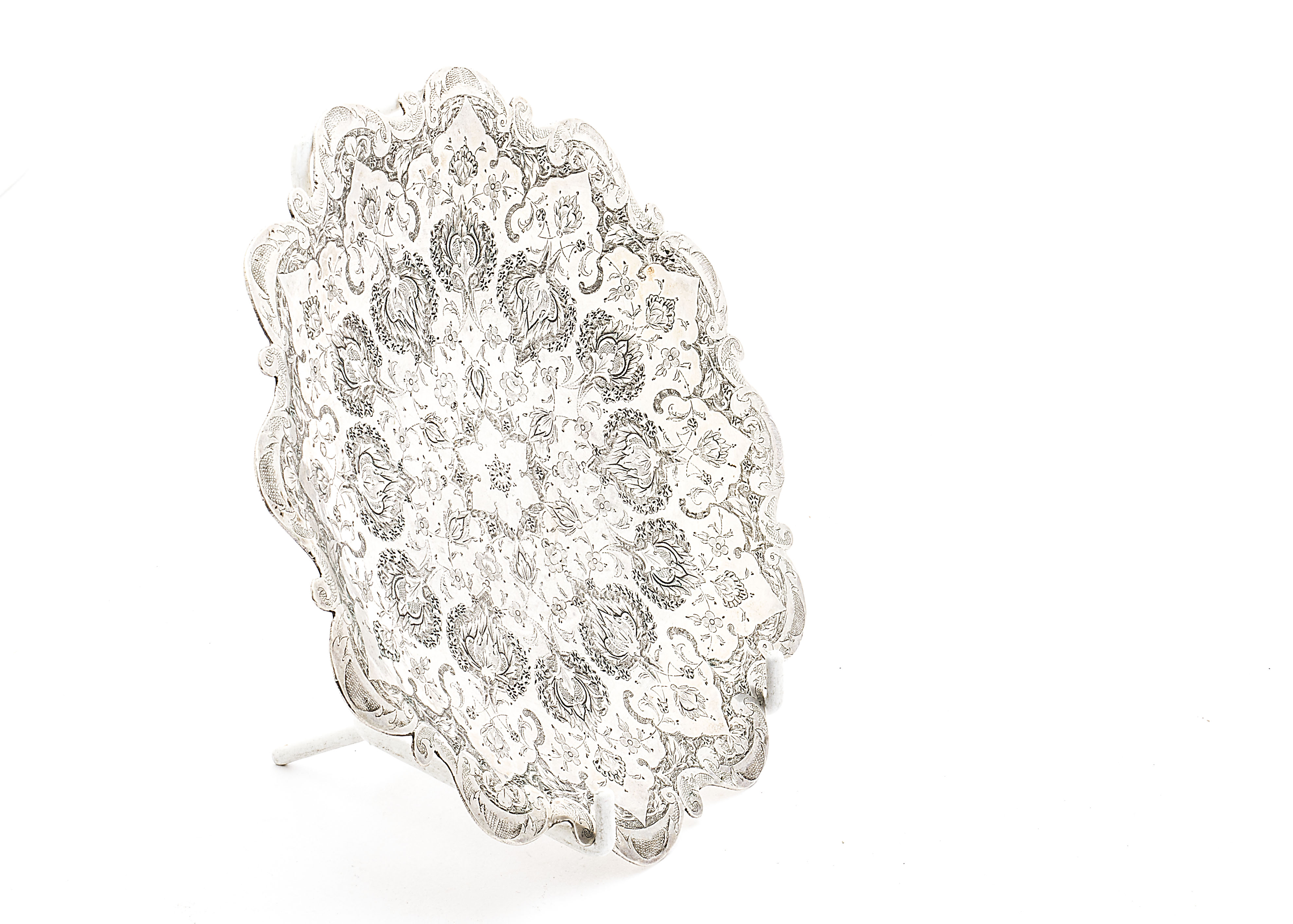 A vintage Middle Eastern white metal dish, with shaped rim and finely engraved floral motifs, strike