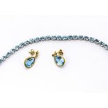 An 18ct gold topaz and diamond set line bracelet, the oval mixed cut blue topaz in claw settings