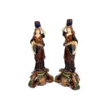 A pair of 19th Century majolica candlesticks, in the form of classical maidens holding a torch and