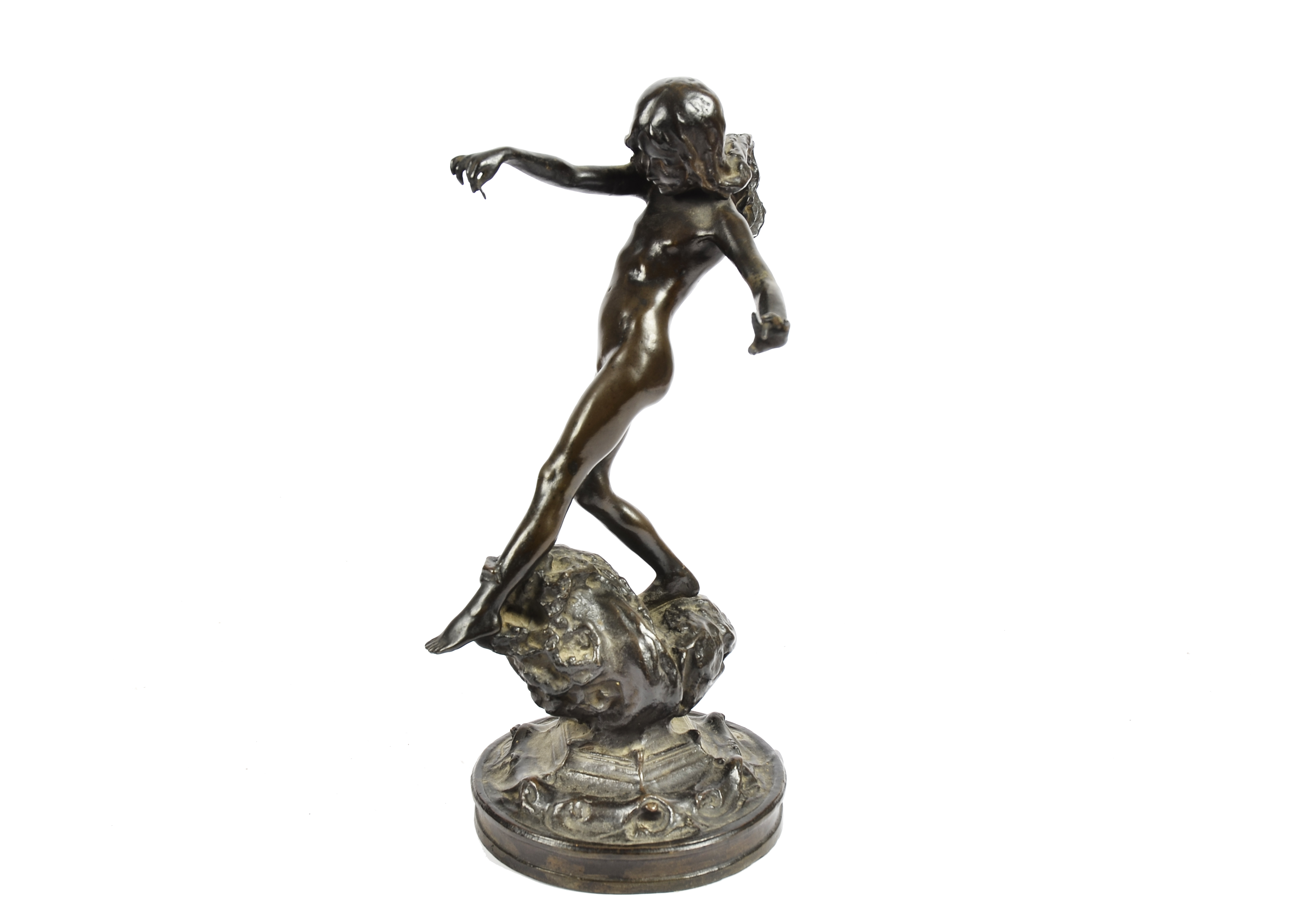 An Art Deco bronze sculpture of a female nude with windswept hair dancing on a rock, circular