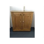 A 19th Century waxed pine cupboard, two panel doors with porcelain handles, fitted shelves, castors,