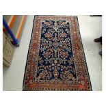 A Persian woollen rug, floral decoration on cobalt ground, terracotta floral border, 212 cm x 127