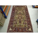 A Persian woollen rug, vase of flowers on green floral field, floral border, 230 cm x 134 cm