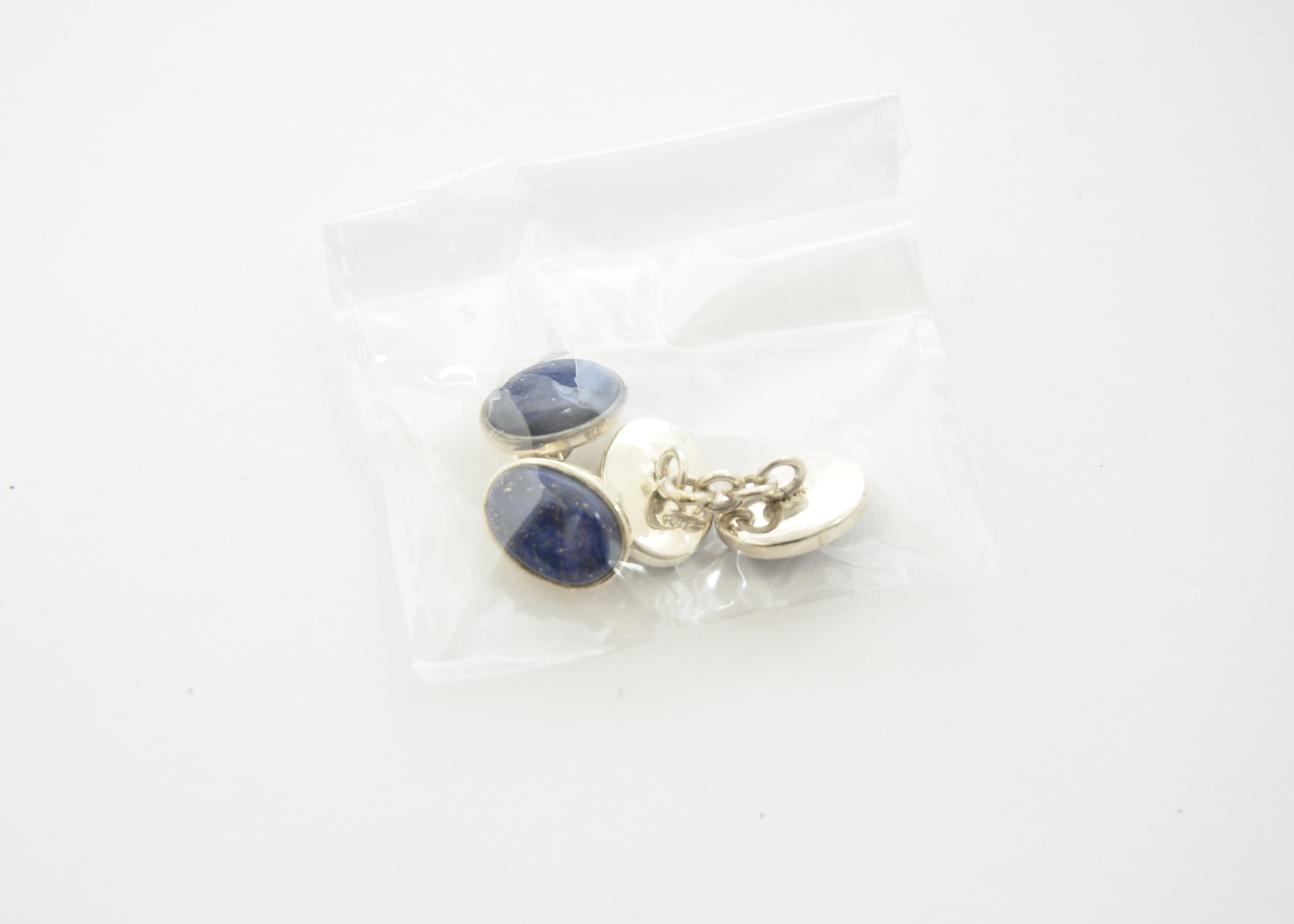 A pair of lapis lazuli cufflinks, each terminal conjoined with white metal chain links, stamped 925