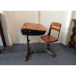 A vintage oak and cast metal child's school desk, inkwell and pen holders to hinged lid, swivel