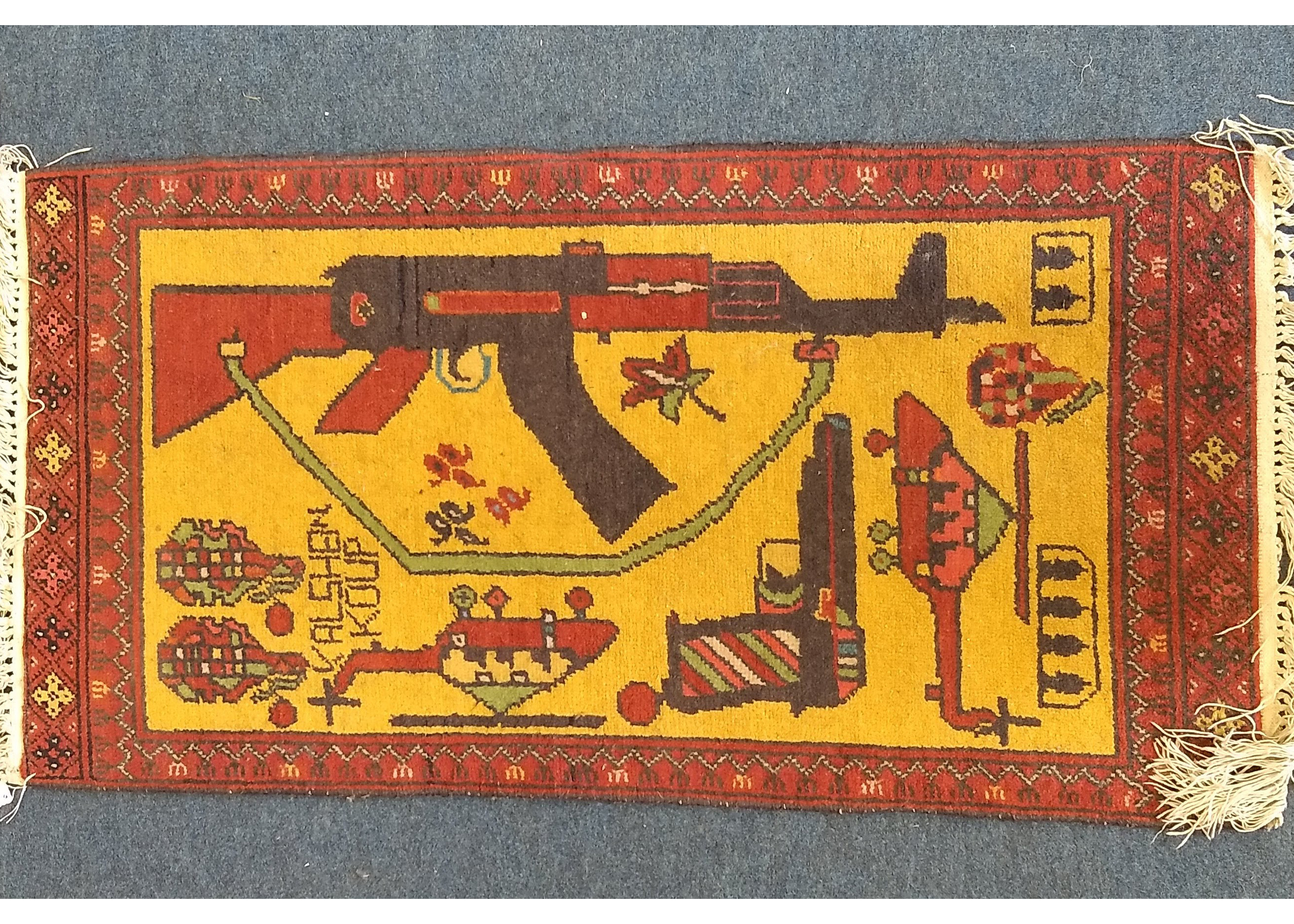 An Afghan woollen war rug, helicopter, guns and grenades on yellow ground, red patterned border, 100