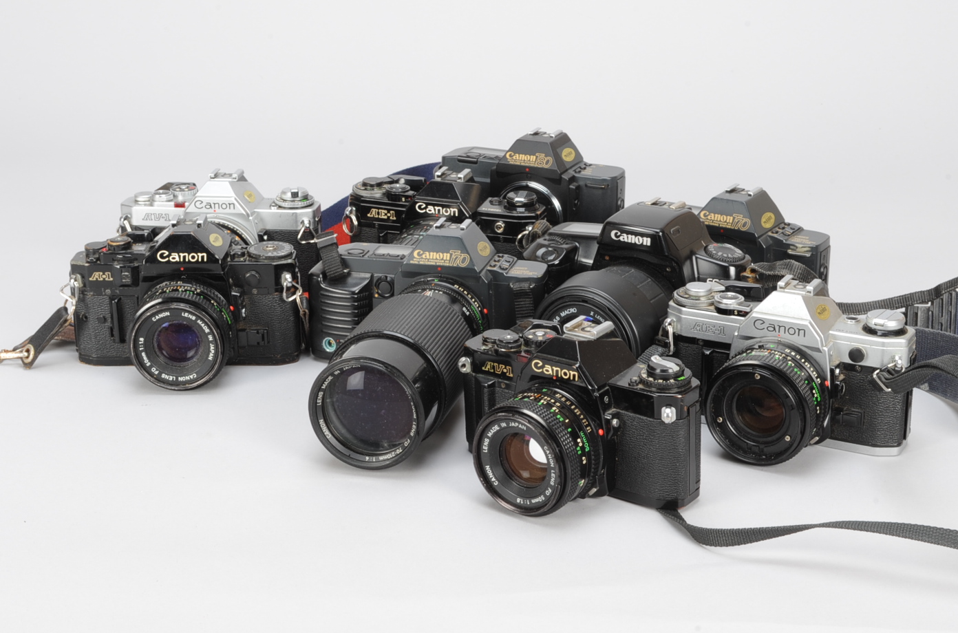 A Tray of Canon SLR Cameras, including a black A1, lens button missing, a black AE-1 , a chrome AE-