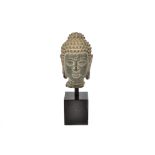 A decorative oriental head of a Buddah, mounted on a square stand, 21 cm high