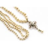 A cultured pearl graduated, knotted necklace, with stylised floral and yellow metal cruciform