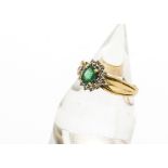 A 14ct gold emerald and diamond cluster ring, the oval cut central emerald claw set surrounded by