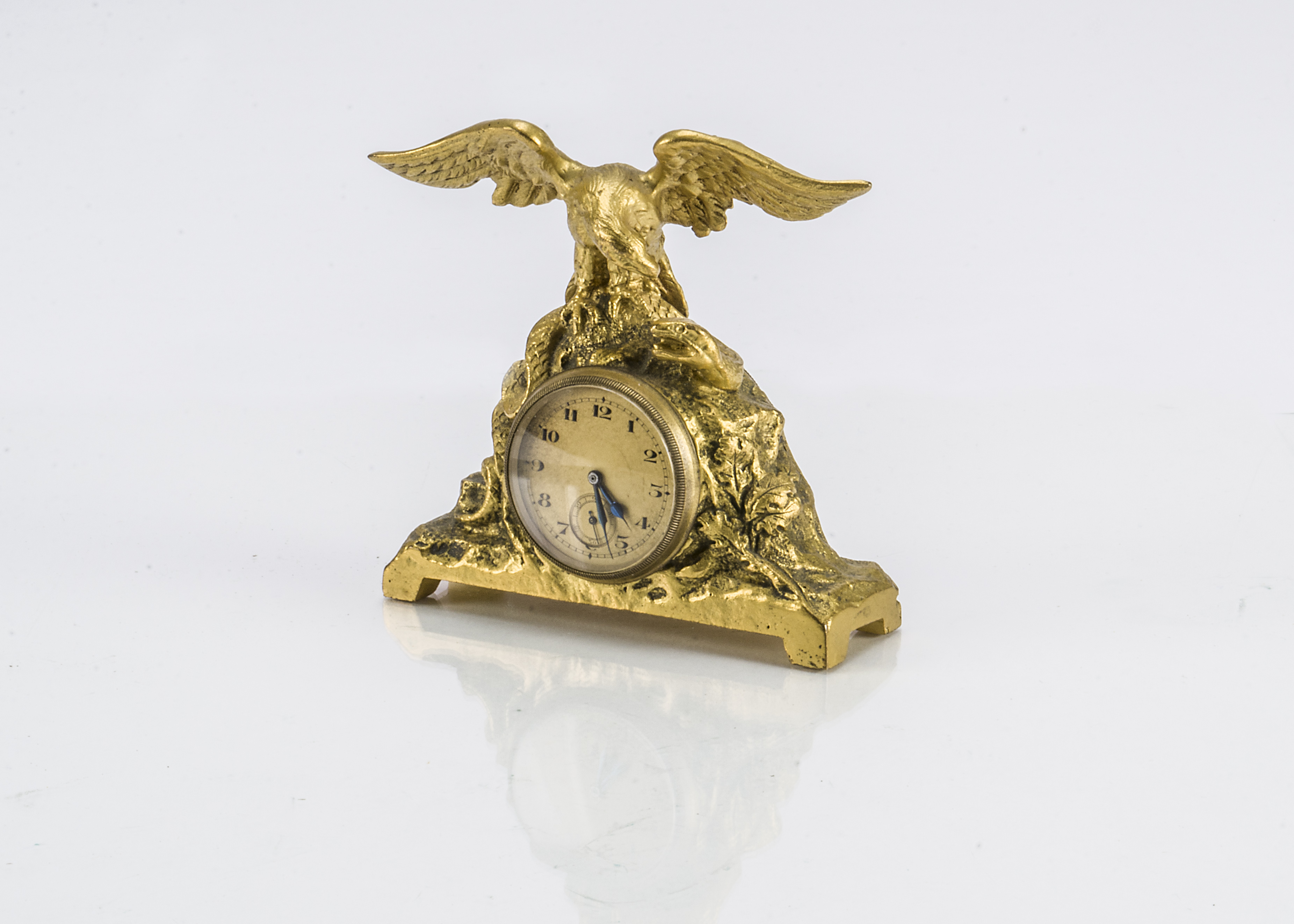A small late 19th century French gilt clock, with eagle and snake on craggy base and inset watch