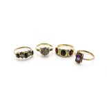 Four gem set gold dress rings, comprising an 18ct gold garnet and diamond three stone dress ring, an