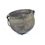 A large 19th Century cast iron cauldron, with a folded rim, standing on three feet, diameter 36 cm