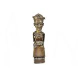 An African Benin bronze figure, modelled as a woman seated whilst holding a bowl, 34 cm high