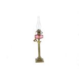 A cranberry glass oil lamp on attractive Corinthian brass column, Edwardian or first quarter of