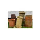 A group of five chimney pots, including two terracotta examples, four round and one square,