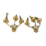 A pair of gilt metal three branch Rococo style wall sconces, with fluted rims and leaf scrolling