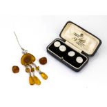 An amber and white metal pin brooch, the pin supporting stylised fleur de lys with boulder amber