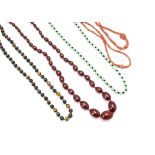 A knotted string of cherry amber style oval beads, 62g, together with two coral necklaces, a