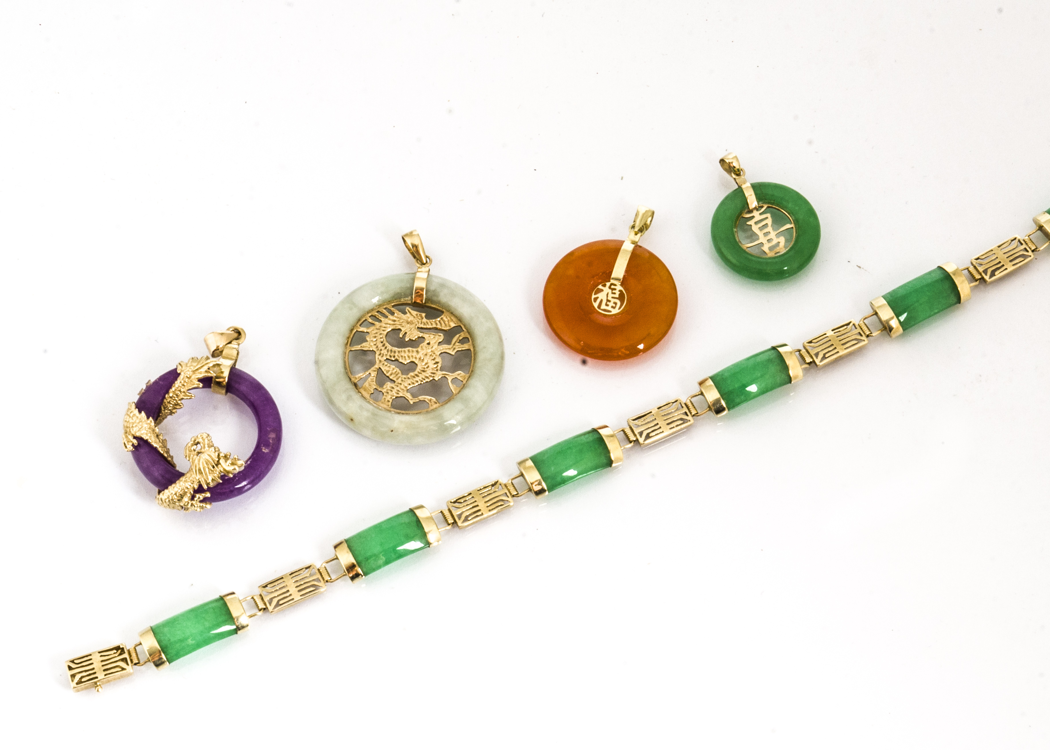 A quantity of coloured jade and hardstone Chinese pendants, and a green jade Chinese bracelet
