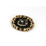A 19th Century yellow metal mourning brooch, with black enamel front piece mounted with seed