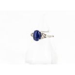 A sapphire and diamond dress ring, in the art deco style, the oval cabochon sapphire flanked by