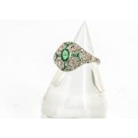 An art deco style emerald and diamond dress ring, the oval central emerald within a fine diamond and