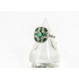An emerald and diamond dress ring, the oval tablet setting with cruciform emerald set centre and