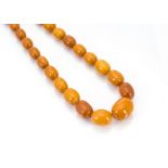 An art deco amber string of graduated oval beads, 28g, 54cm long