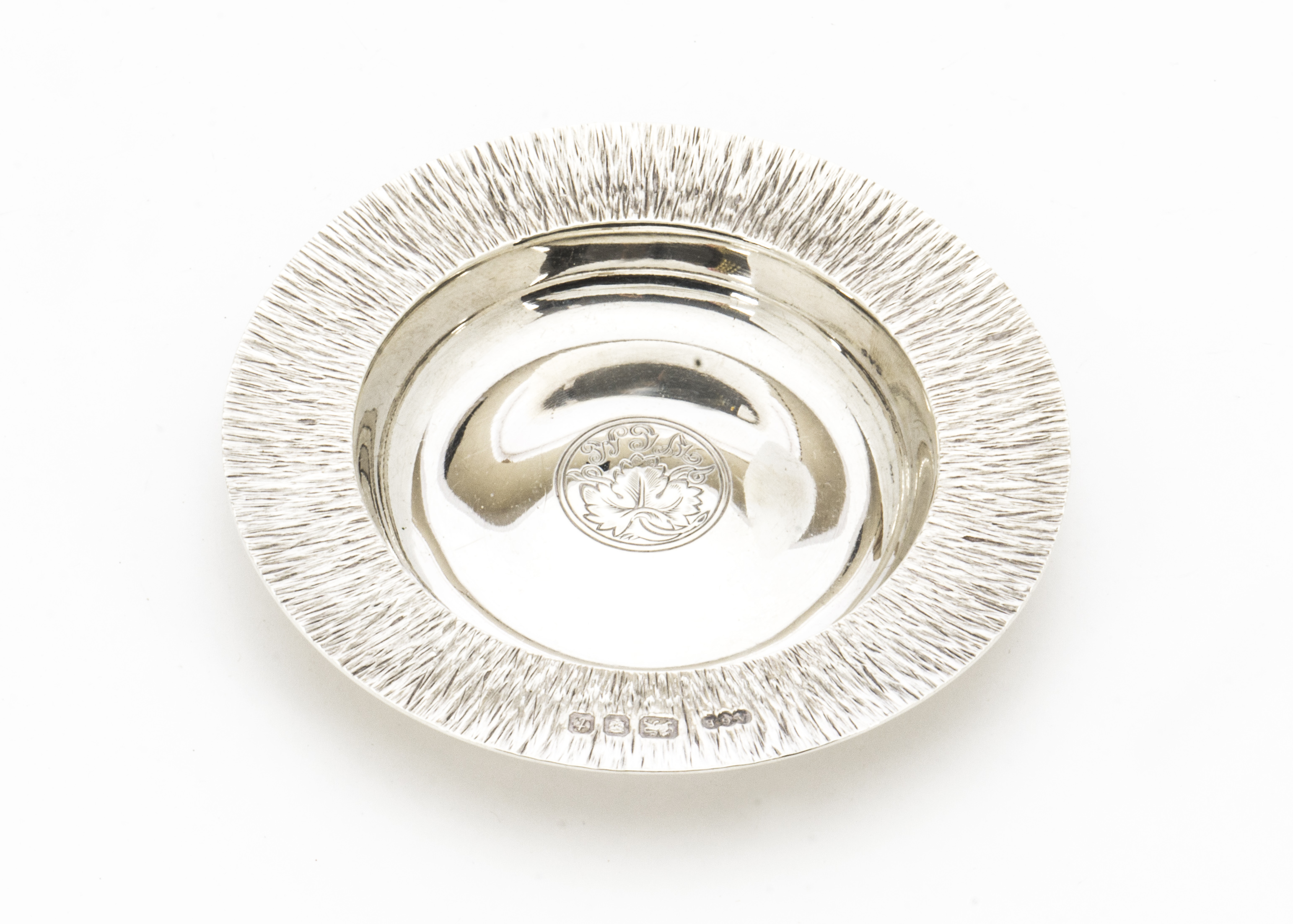 A 1970s silver dish by Gerald Benney, circular having bark effect textured rim and engraved grape