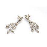 A pair of white metal and paste drop earrings, the three drop set studs supporting bell like