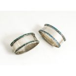 A Pair of George V silver and enamelled napkin rings from Liberty & Co, elliptical with a band of