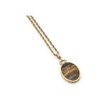 A 9ct gold tiger's eye and moss agate medallion, the oval floral chased mount with ornate scroll and