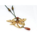 An art nouveau horn pendant, in the form of a dragonfly within a circular mount supporting a glass