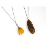 An early 20th Century white metal mounted amber boulder pendant, in toffee colour, together with a