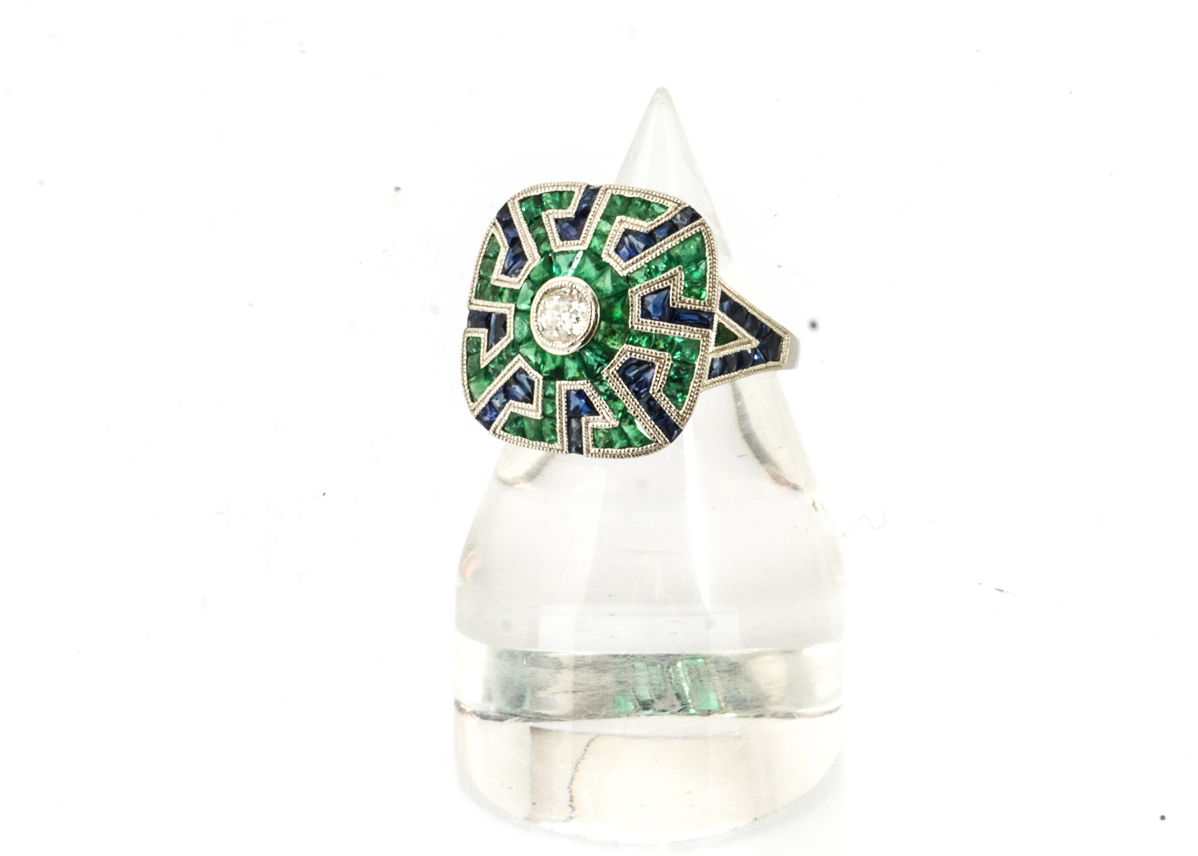An art deco style diamond, emerald and sapphire dress ring, old cut diamond centred within an