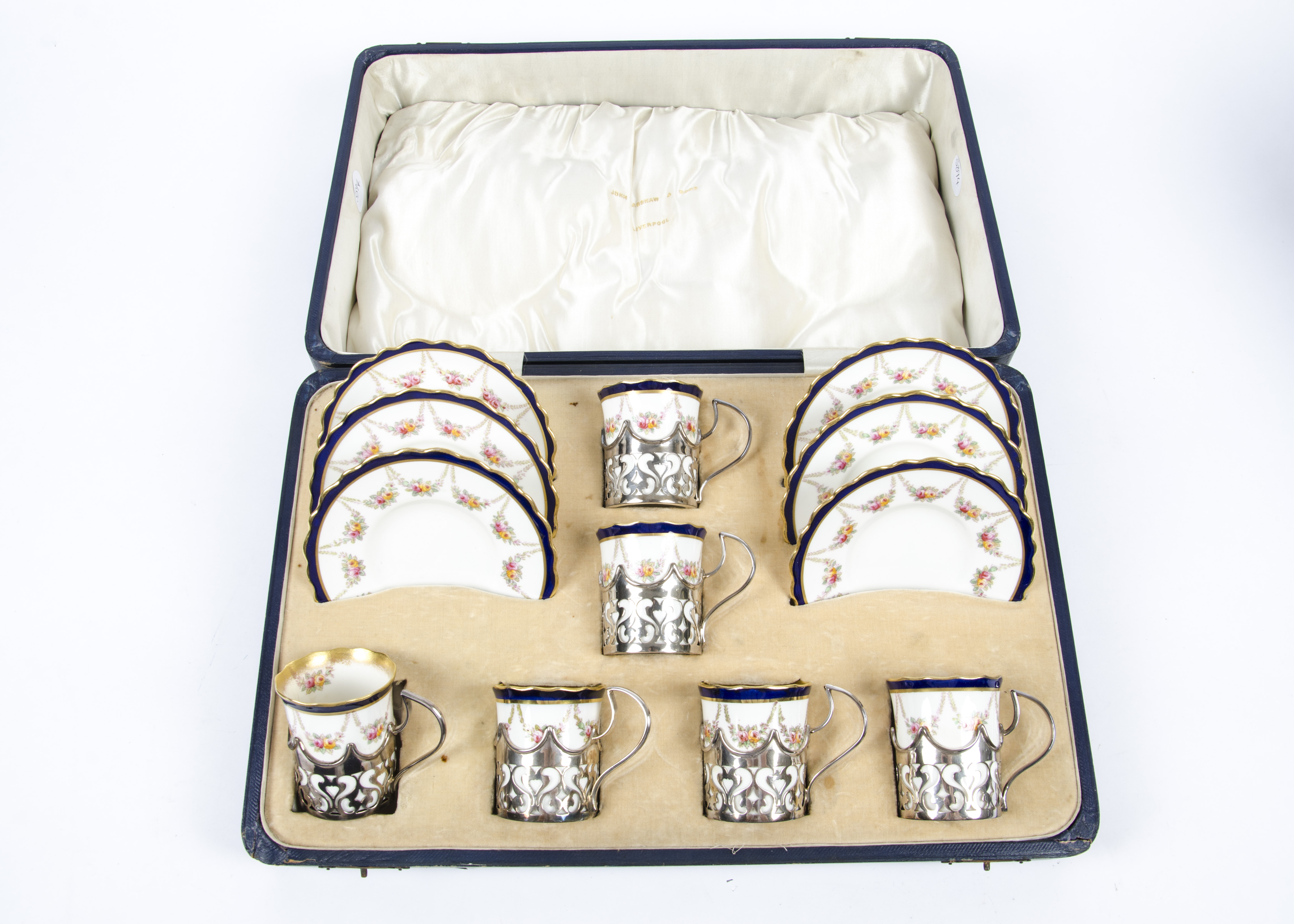 An Aynsley coffee set of six cups and saucers, with blue and gilt borders above arched floral