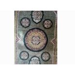 An attractive rug accented mostly in green with multiple repeating border patterns, the central