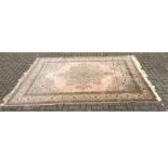 A large 20th Century silk rug, with a floral border and central motif on a pale silk ground and