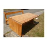 A contemporary pitch pine refectory table, with hinged flap to one side, on two shaped supports,