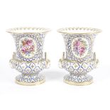 A Sevres style French porcelain pair of urns, of campagna shape with two handles taking the form