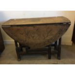 An antique oak circular gate leg table, single drawer to one end, later carving to top and