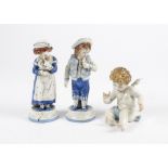 A continental porcelain putti figure, together with a pair of Victorian continental figures of boy
