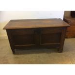 An antique oak coffer, with two plain panels to front with later carving to the surround and