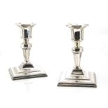 A pair of Edwardian silver filled candlesticks, square base with short stems and integrated