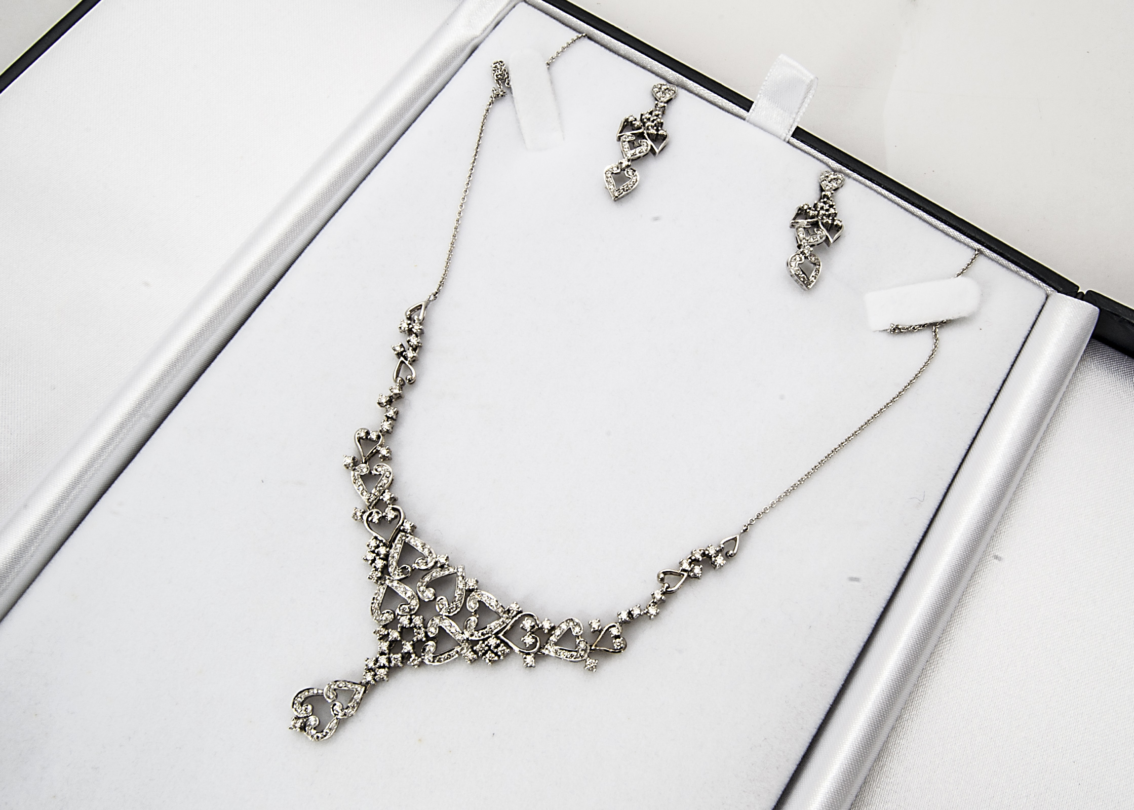 A contemporary diamond necklace and matching earrings, the heart shaped necklace encrusted with