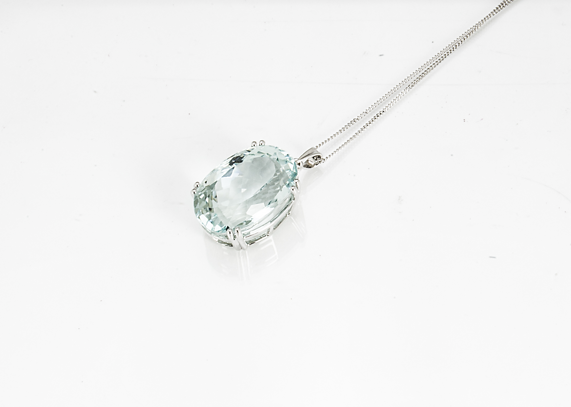 A contemporary large aquamarine drop pendant, of oval mixed cut, the mint green aqua in four claw